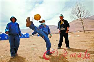 草地上,男孩子們在踢球。地震不能抹殺孩子的快樂。